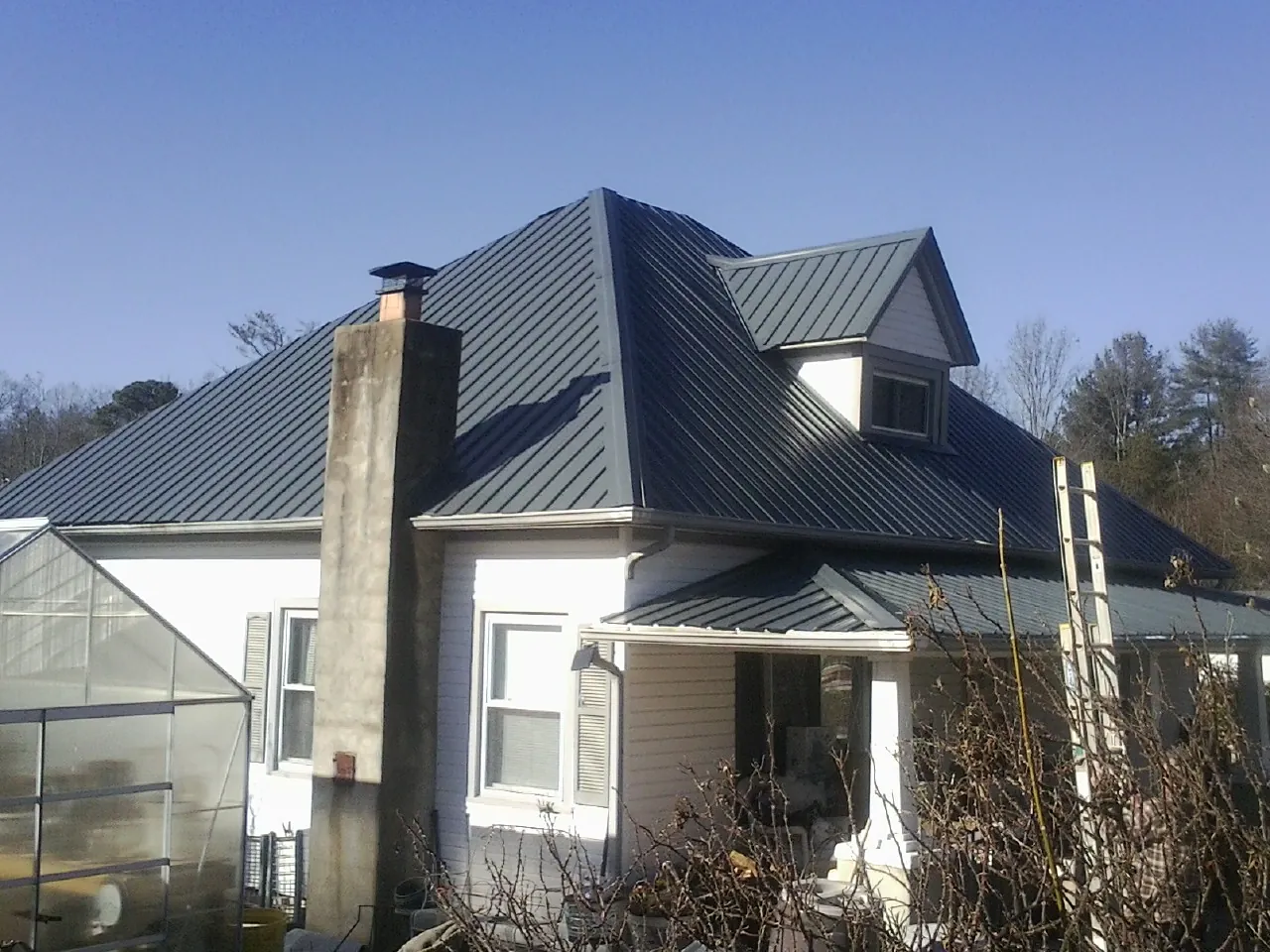 Dark blue standing seam metal roof on a white farmhouse with dormer — Slate & Tile Roof Repair by Roofing Brothers in Tremont City