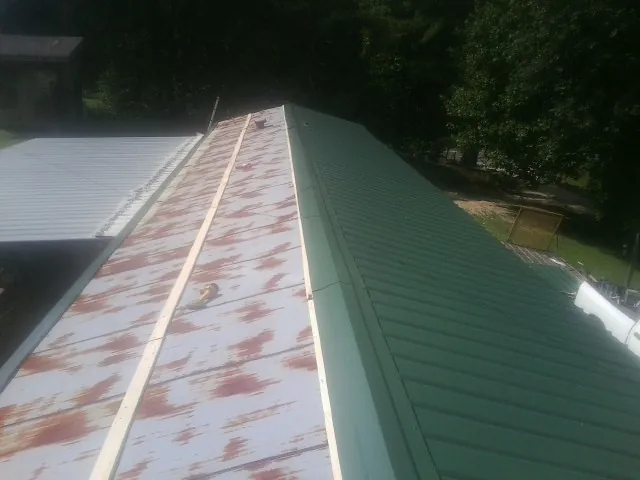 Old rusted panels beside newly installed green metal roofing — Wind Damage Roof Repair by Roofing Brothers in Tremont City