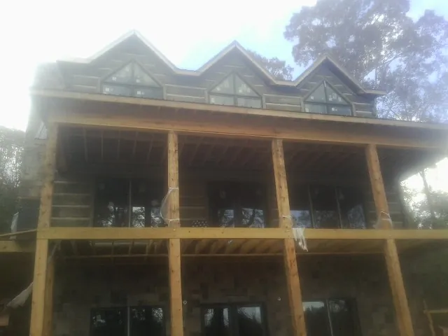 Dormers and porch framing on a large log home under construction — Roof Coating work by our crew in Tremont City