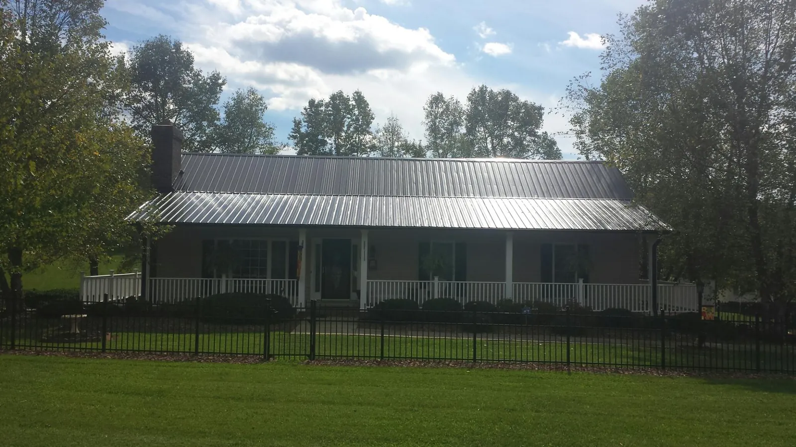 Gray metal roof on a brick ranch with a full width front porch — Gutter Guard Installation work by our crew in Tremont City