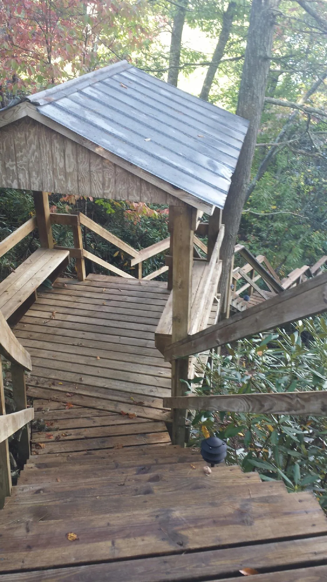 Metal roofed shelter over wooden steps on a wooded walkway — Skylight Repair & Installation work by our crew in Tremont City