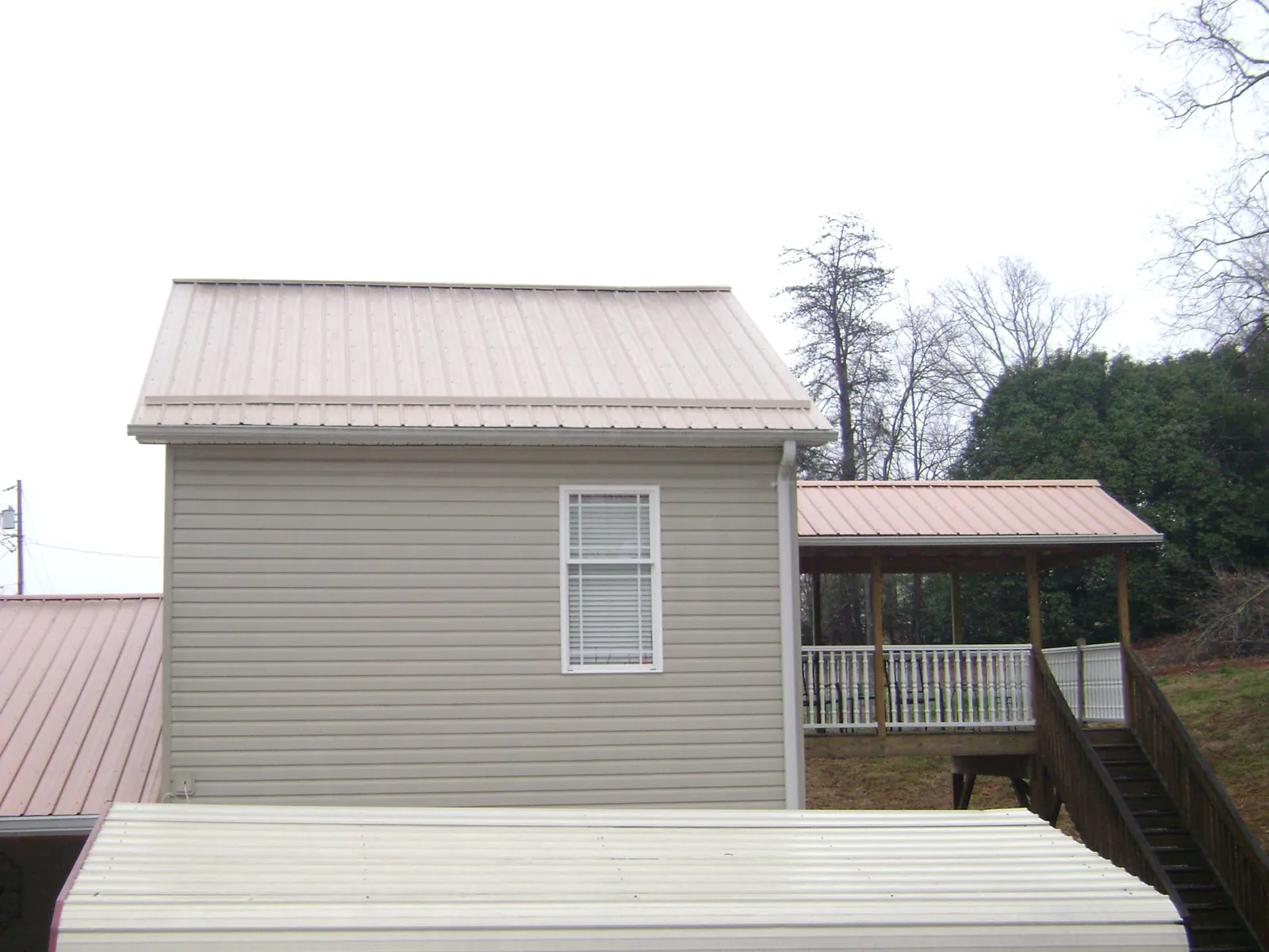 Tan metal roofs on a two story addition and attached porch, from a Roof Replacement job in Tremont City