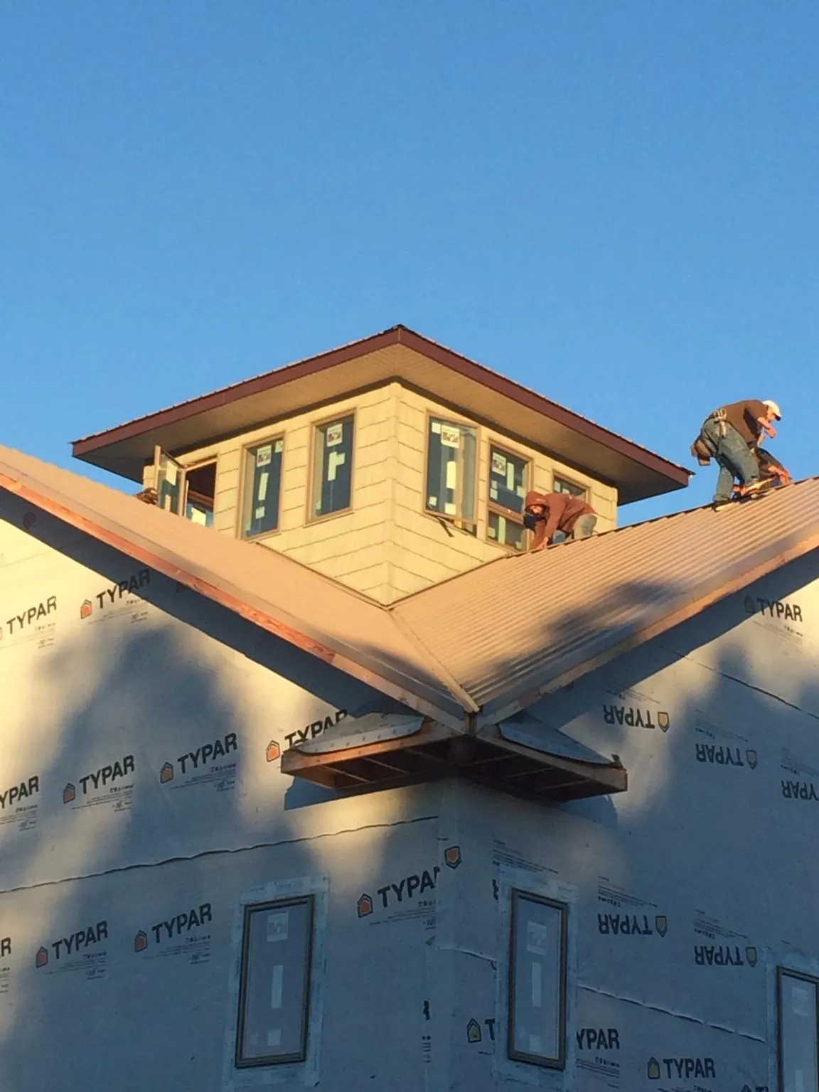 Roofers working around a rooftop cupola on a new metal roof at sunset — Roof Waterproofing in Tremont City by Roofing Brothers